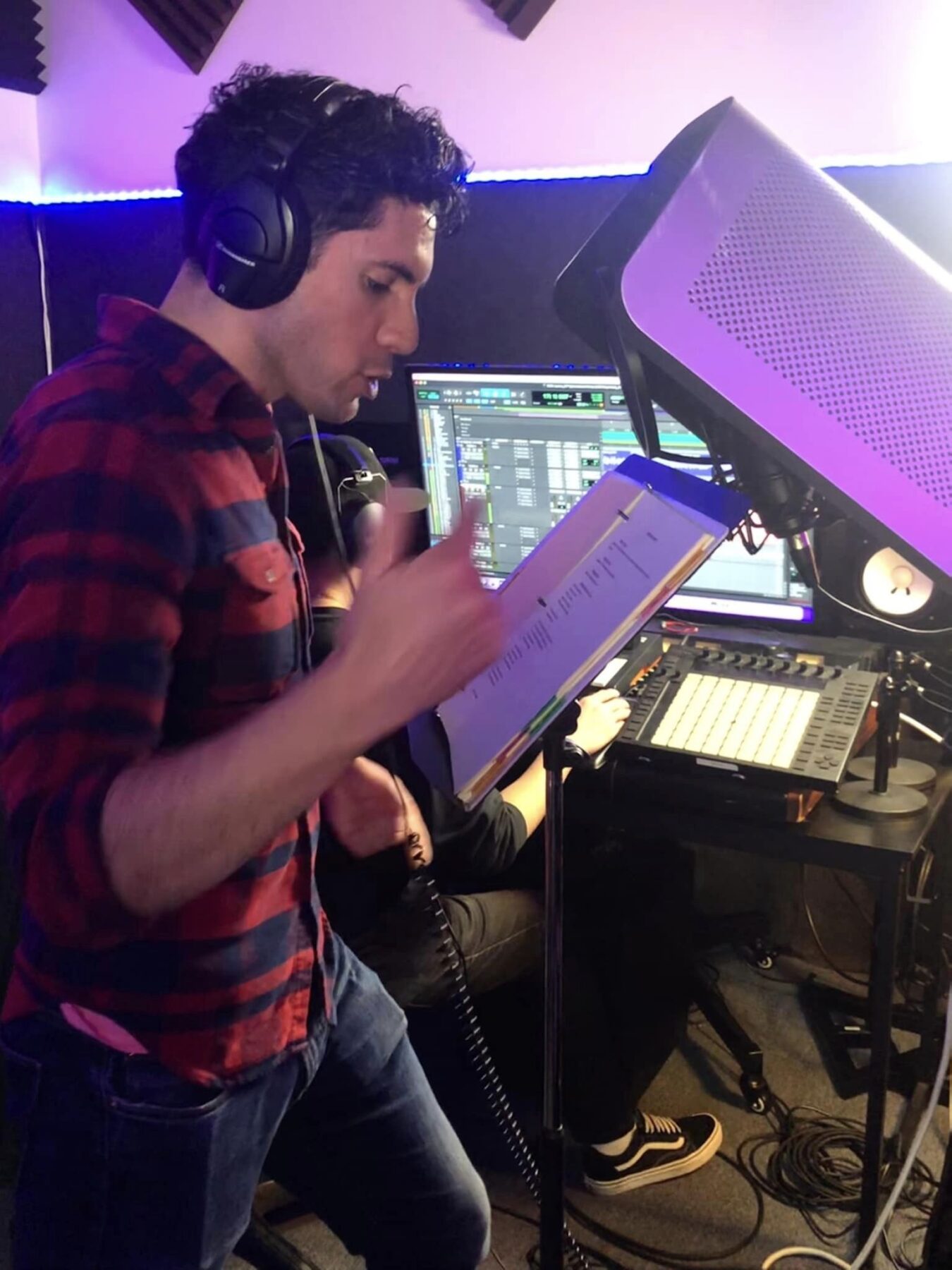 Eric Delgado, a young Latino man singing into microphone in recording studio